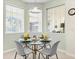 Cozy breakfast nook boasts large windows, pendant lighting, and seating for four around a glass table at 407 Grand Reserve Dr, Davenport, FL 33837