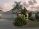 Exterior elevation of home with a well-manicured lawn, palm tree, and two car garage at 407 Grand Reserve Dr, Davenport, FL 33837