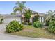 Inviting single-story home featuring a well-manicured lawn and lush tropical landscaping at 407 Grand Reserve Dr, Davenport, FL 33837