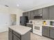 Modern kitchen with gray cabinets, stainless appliances, white countertop island, and an adjacent laundry room at 407 Grand Reserve Dr, Davenport, FL 33837