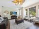 Cozy living room featuring wood floors, a ceiling fan, a leather sofa and large windows at 407 Grand Reserve Dr, Davenport, FL 33837