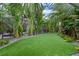 Lush backyard with manicured artificial turf surrounded by a variety of tropical plants and trees at 418 Gleaming Andover Way, Longwood, FL 32779