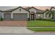 Home exterior showcases neutral tones, stone accents, an arched entryway and lush, green landscaping at 418 Gleaming Andover Way, Longwood, FL 32779
