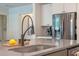 Close-up of a kitchen island with a modern faucet, sink, and stainless steel appliances in the background at 418 Gleaming Andover Way, Longwood, FL 32779