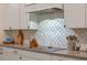 Close-up of kitchen featuring white cabinetry, decorative backsplash, and stainless steel stovetop at 418 Gleaming Andover Way, Longwood, FL 32779