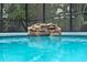 Close-up of the cascading waterfall feature in the sparkling screened-in pool at 418 Gleaming Andover Way, Longwood, FL 32779