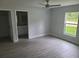 This bedroom features grey wood floors, a ceiling fan and window views of lush greenery at 4333 Sw 157Th Ter, Ocala, FL 34481