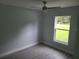 This bedroom features grey wood floors, a ceiling fan and window views of the yard at 4333 Sw 157Th Ter, Ocala, FL 34481
