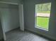 This bedroom features grey wood floors, a closet and window views of lush greenery at 4333 Sw 157Th Ter, Ocala, FL 34481