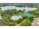 Aerial view of a community pool, tennis court, basketball court, and lake surrounded by lush greenery at 5063 Carillon Ln, Windermere, FL 34786