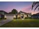 Charming single-story home featuring a well-manicured lawn and attached two car garage at dusk at 610 Strihal Loop, Oakland, FL 34787
