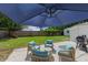 Backyard patio featuring outdoor furniture with large umbrella, grill, and green lawn at 63 Madera Rd, Debary, FL 32713