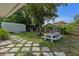 Landscaped backyard featuring stone patio, white picnic table, mature trees and storage shed at 63 Madera Rd, Debary, FL 32713