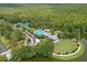 Beautiful aerial view of a tennis court, pool, park, and lake with forest backdrop at 720 Celebration Ave # 245, Kissimmee, FL 34747