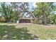Large backyard with mature trees, a patio, a trampoline, and a partial view of the house at 881 Cedar Cir, Tavares, FL 32778