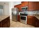 Kitchen with stainless steel appliances, granite countertops and backsplash and warm wood cabinetry at 1061 Citrus Landings Blvd, Davenport, FL 33837