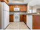 Well-equipped kitchen with white appliances, granite countertops, and warm wood cabinetry at 1101 Vintage Village Ln # 101, Ocoee, FL 34761