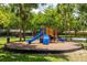 Community playground surrounded by mature trees and a black mulch perimeter at 1101 Vintage Village Ln # 101, Ocoee, FL 34761