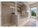 Well-lit bathroom with a glass-enclosed shower, soaking tub, neutral tiling and view to the outside at 1200 Ironsmith Dr # 508, Celebration, FL 34747