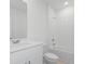 Clean, white bathroom featuring a vanity, toilet, and shower-tub combination with tiled walls at 1345 Griffon Ave, Lake Alfred, FL 33850