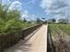 Wooden bridge leading to a community area with a playground and houses, perfect for Gathering walks and outdoor activities at 1345 Griffon Ave, Lake Alfred, FL 33850