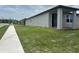 New home's side exterior, featuring a well-manicured lawn and view of the adjacent neighborhood at 1345 Griffon Ave, Lake Alfred, FL 33850