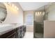 Bathroom featuring dual vanities, granite counters, arched window, and a tiled glass shower with a built-in seat at 139 Andrews Rd, Sanford, FL 32773