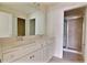 Bright bathroom featuring a double vanity, a large mirror, and a glass-enclosed shower with tile surround at 16129 Palm Frond Ave, Clermont, FL 34714