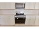 Modern kitchen featuring stainless steel microwave and electric range with white cabinets at 16129 Palm Frond Ave, Clermont, FL 34714