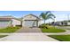 Charming single-story home featuring a paved driveway, manicured lawn, and lush landscaping with palm tree at 1650 Key Bay Trl, Kissimmee, FL 34747