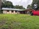 Ranch home showing covered parking, stone accents, and landscaping, including a red dumpster and overcast sky at 2035 Voltaire St, Lakeland, FL 33801