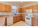Functional kitchen with wood cabinets, matching appliances, tile backsplash, and neutral countertops at 223 Monterey St, Kissimmee, FL 34759