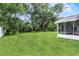 Spacious backyard with mature trees, grassy lawn, and partial view of screened patio at 229 Marcum Trace Dr, Lakeland, FL 33809