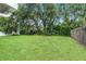 Large grassy backyard with mature trees and a wood fence along the property line at 229 Marcum Trace Dr, Lakeland, FL 33809