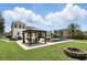 A beautiful backyard offers a covered outdoor dining area, sparkling pool, green lawn, and fire pit at 2908 Lee Shore Loop, Orlando, FL 32820