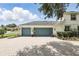 Spacious three-car garage with teal doors and a brick paver driveway, adding curb appeal to the home's exterior at 2908 Lee Shore Loop, Orlando, FL 32820