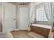 Bathroom featuring a soaking tub with tile surround and a window with decorative curtains at 3201 Oaklea Dr, Deland, FL 32720