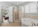Bright bathroom featuring a glass-enclosed shower and soaking tub with white shutters at 405 Courtlea Park Dr, Winter Garden, FL 34787
