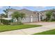 Charming home with a two-car garage, brick driveway, green lawn, and mature palm trees in the front yard at 405 Courtlea Park Dr, Winter Garden, FL 34787