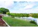 Spacious backyard with lush green grass and tranquil pond view, enclosed by a classic white fence at 4642 Waterside Pointe Cir, Orlando, FL 32829