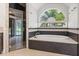 Relaxing bathroom with a soaking tub under an arch window, a glass enclosed shower and elegant finishes at 685 Mayo Ave, Maitland, FL 32751