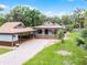 Inviting home with a covered porch, porte-cochere, brick-paved driveway, and lush landscaping at 740 Florida Blvd, Altamonte Springs, FL 32701
