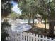 A community pool area is shown with a hot tub enclosed by a white picket fence, surrounded by mature trees for shade and privacy at 7900 S Orange Blossom Trl # 2108, Orlando, FL 32809