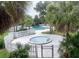 A community pool with hot tub is shown enclosed by white fencing and tropical landscaping at 7900 S Orange Blossom Trl # 2108, Orlando, FL 32809