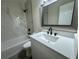 Updated bathroom features a quartz vanity, framed mirror, tub with tile surround and sleek fixtures at 8320 Dominguin St, Orlando, FL 32817