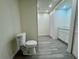 A recently renovated bathroom showcases a toilet, modern cabinets and drawers, and gray wood floors at 8320 Dominguin St, Orlando, FL 32817