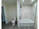 The modern bathroom features a toilet, tub, elegant marble tile, and gray wood floors at 8320 Dominguin St, Orlando, FL 32817