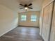 A sun-filled bedroom with a ceiling fan, two windows, and a closet is well-lit and features gray wood floors at 8320 Dominguin St, Orlando, FL 32817