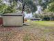 View of the backyard with a shed and a screened-in porch, surrounded by mature trees at 8404 Singapore Ct, Orlando, FL 32817