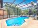 Screened-in pool with blue water and tiled edge, surrounded by tropical plants for privacy at 12641 Arley Dr, Windermere, FL 34786